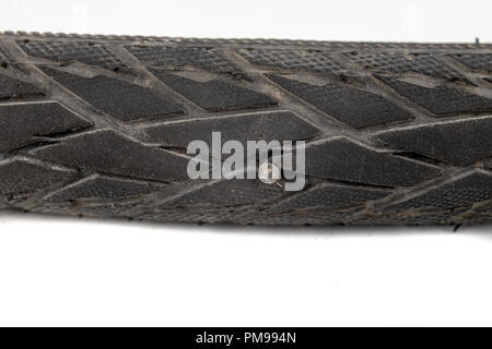 A beaten bicycle tire in the workshop. A bicycle wheel pierced with a nail. Light background. Stock Photo