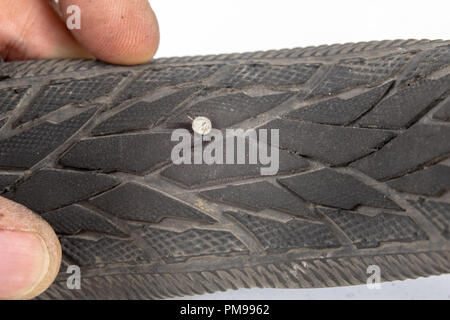 A beaten bicycle tire in the workshop. A bicycle wheel pierced with a nail. Light background. Stock Photo