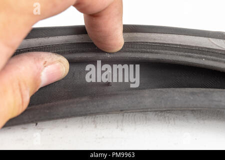 A beaten bicycle tire in the workshop. A bicycle wheel pierced with a nail. Light background. Stock Photo