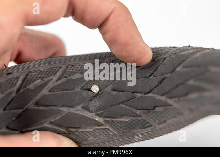 A beaten bicycle tire in the workshop. A bicycle wheel pierced with a nail. Light background. Stock Photo
