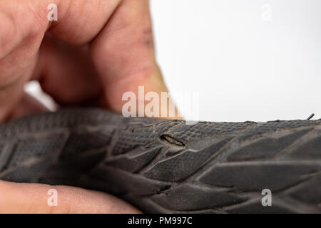 A beaten bicycle tire in the workshop. A bicycle wheel pierced with a nail. Light background. Stock Photo