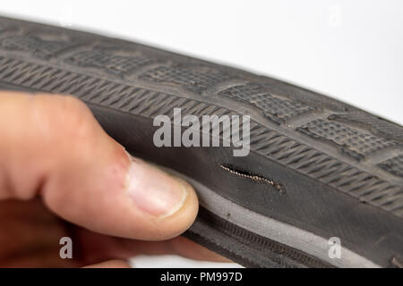 A beaten bicycle tire in the workshop. A bicycle wheel pierced with a nail. Light background. Stock Photo