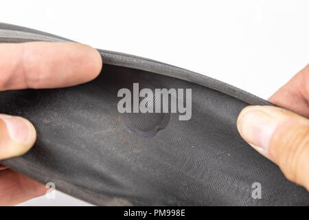 A beaten bicycle tire in the workshop. A bicycle wheel pierced with a nail. Light background. Stock Photo