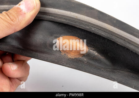 A beaten bicycle tire in the workshop. A bicycle wheel pierced with a nail. Light background. Stock Photo