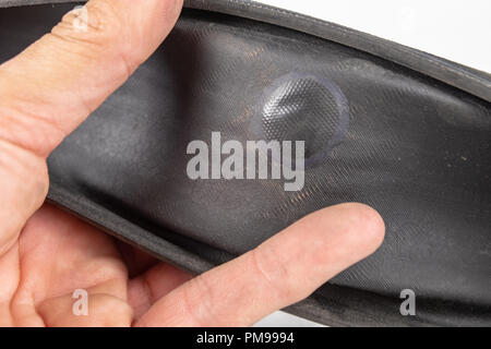 A beaten bicycle tire in the workshop. A bicycle wheel pierced with a nail. Light background. Stock Photo