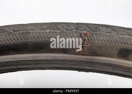 A beaten bicycle tire in the workshop. A bicycle wheel pierced with a nail. Light background. Stock Photo