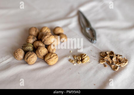 Nutcracker and walnuts in a bowl on a table covered with a tablecloth. Snack on the kitchen table. Light background. Stock Photo