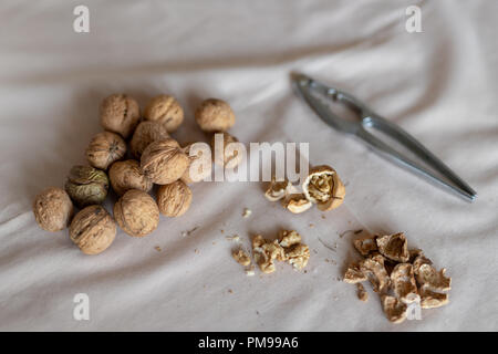 Nutcracker and walnuts in a bowl on a table covered with a tablecloth. Snack on the kitchen table. Light background. Stock Photo