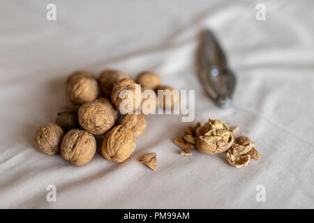 Nutcracker and walnuts in a bowl on a table covered with a tablecloth. Snack on the kitchen table. Light background. Stock Photo
