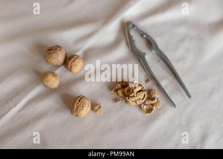 Nutcracker and walnuts in a bowl on a table covered with a tablecloth. Snack on the kitchen table. Light background. Stock Photo