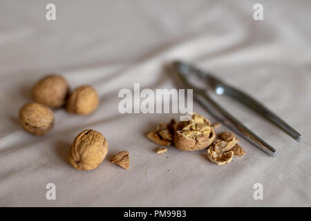 Nutcracker and walnuts in a bowl on a table covered with a tablecloth. Snack on the kitchen table. Light background. Stock Photo