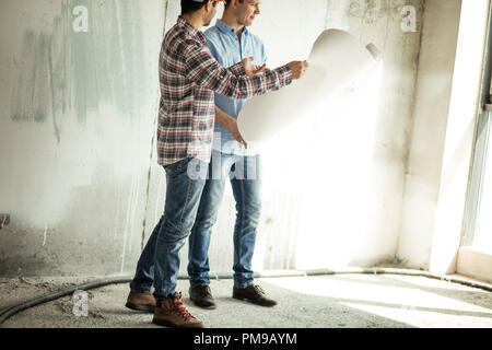 side view cropped photo of two cheerful guys using blueprint at work Stock Photo