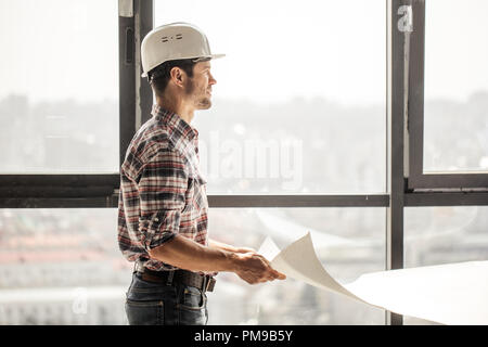 handsome builder is looking away and slitting his eyes Stock Photo