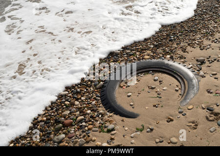 Old vehicle wheel and tyre embedded in sand on the beach at Seaham, Co. Durham, England, UK Stock Photo