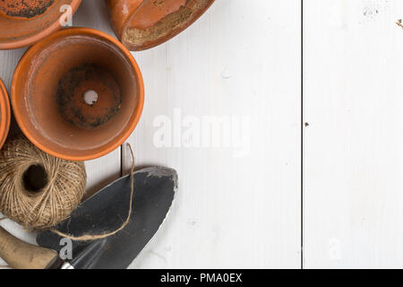 Group of empty, used terracotta planting pots with gardening tools on white wooden table from above top view flatlay Stock Photo