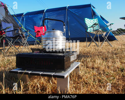 A kettle on a gas camp oven with tents in the background Stock Photo