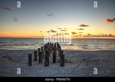 Dilapidated ruins of a pier on Port Royal Beach at sunset in Naples, Florida Stock Photo