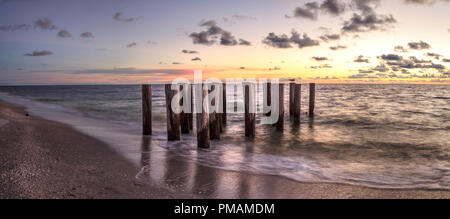 Dilapidated ruins of a pier on Port Royal Beach at sunset in Naples, Florida Stock Photo