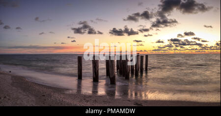 Dilapidated ruins of a pier on Port Royal Beach at sunset in Naples, Florida Stock Photo