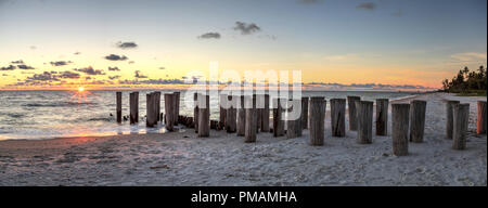 Dilapidated ruins of a pier on Port Royal Beach at sunset in Naples, Florida Stock Photo