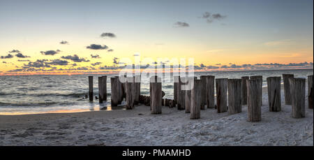 Dilapidated ruins of a pier on Port Royal Beach at sunset in Naples, Florida Stock Photo