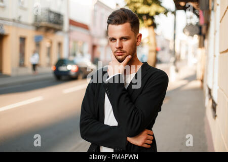 Handsome stylish young man in business clothes posing on the street Stock Photo