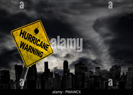 Hurricane warning sign against a powerful stormy background with city silhouette and copy space. Dirty and angled sign with cyclonic winds add to the  Stock Photo