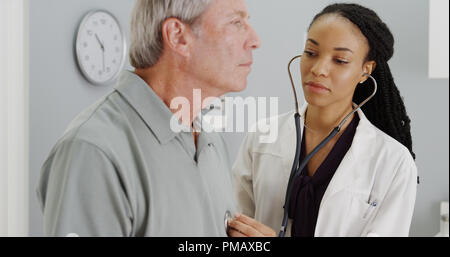 Black doctor listening to senior breathing Stock Photo