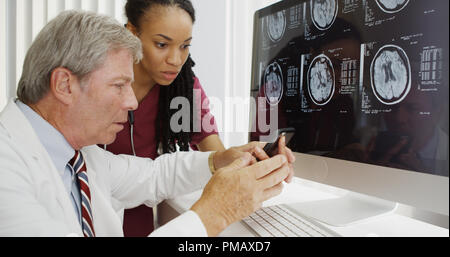 Two doctors analyzing brain xrays on computer Stock Photo