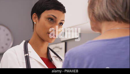 Young intelligent female doctor talking to elderly patient Stock Photo