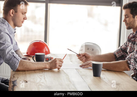 two architects are having fun with a pen and a pencil while drinking Stock Photo