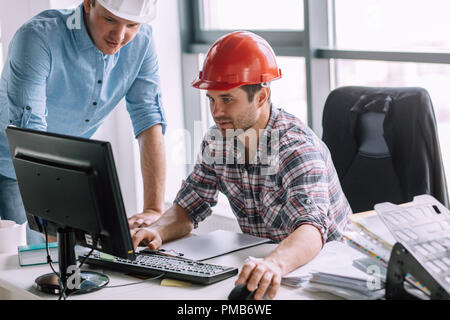 young ambitious constructor with his partner are doing the model of building Stock Photo