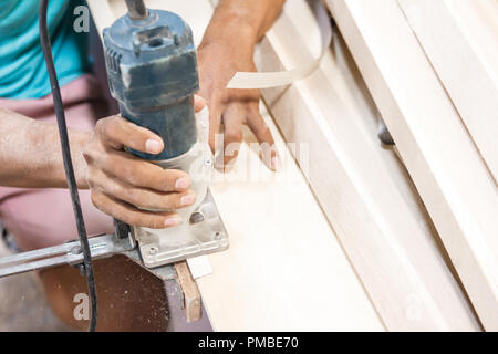 workers hands cutting the edge of wood board using fret saw Stock Photo