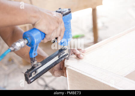 worker at carpenter workspace installing nail using pneumatic na Stock Photo