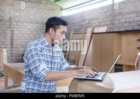 young carpenter working on his laptop Stock Photo