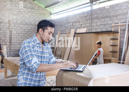 young carpenter working on his laptop Stock Photo