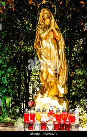 The gilded statue of Madonna in front of St Jacob's Church in Opatija, Croatia with beautiful cardholders in red glass Stock Photo