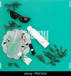 On a light green background are cosmetics: lipstick, cream, liquid soap on a napkin, next to them black glasses. Stock Photo