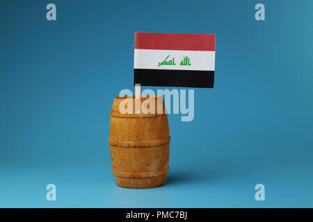 A national flag of Iraq on wooden stick in wooden barrel. Blue background Stock Photo