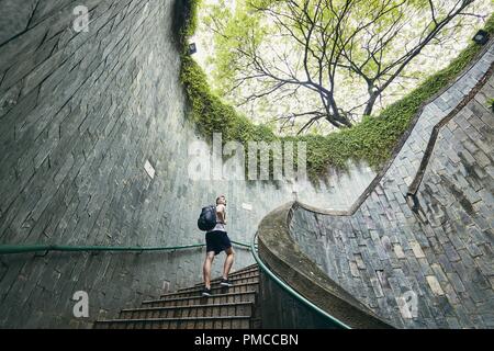 Young man (tourist) walking up on the spiral staircase of underground walkway in Singapore. Stock Photo