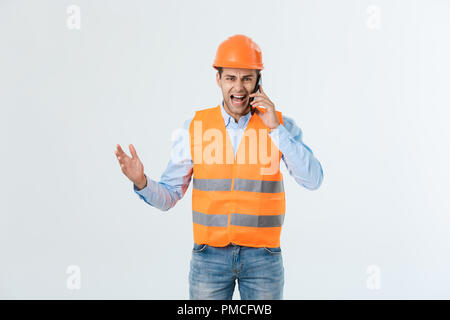 Construction engineer talking on mobile phone, serious adult male person using smartphone for communication with workers on building site. Stock Photo