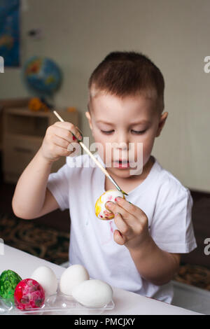 the boy paints eggs with dyes - Easter hand-made articles, children's creativity, development, religious Christian training Stock Photo