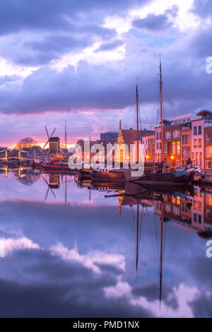 View of the canals of the city of Leiden with hoses, ships and boats at sunset. View of city channel with ships, the city of Leiden, Netherlands. Stock Photo