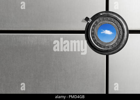 An round aperture in an metal paneling shows blue sky, horizontal. Stock Photo