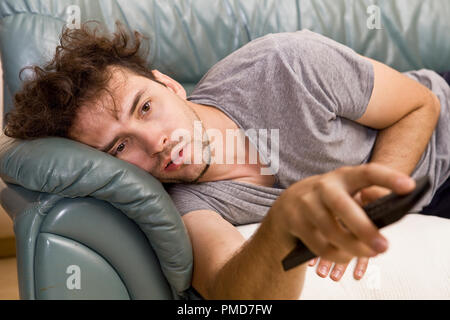 A young man watches television and changes channels while relaxing Stock Photo