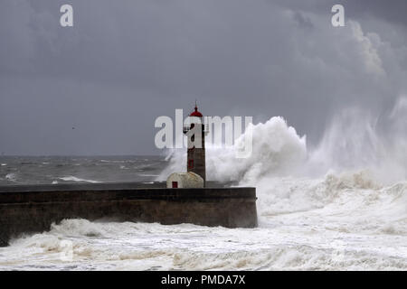 Big white waves over piers and lighthouse against a stormy dark cloudy sky. Douro river mouth, Porto, Portugal. Stock Photo