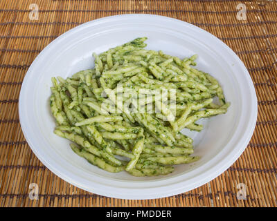 dish of trofie al pesto on a straw place mat : traditional handmade pasta with basil sauce made in Genoa (Liguria Italy) Stock Photo