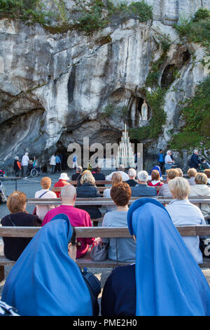 Lourdes (south-western France): grotto of Massabielle, Our Lady of Lourdes sanctuary. Faithful praying in front of the grotto (not available for postc Stock Photo