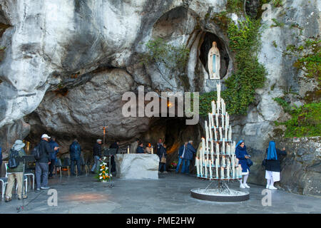 Lourdes (south-western France): grotto of Massabielle, Our Lady of Lourdes sanctuary. Faithful praying in front of the grotto (not available for postc Stock Photo