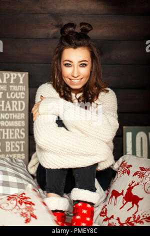 Happy funny young girl in a knitted vintage sweater and red socks on the bed Stock Photo